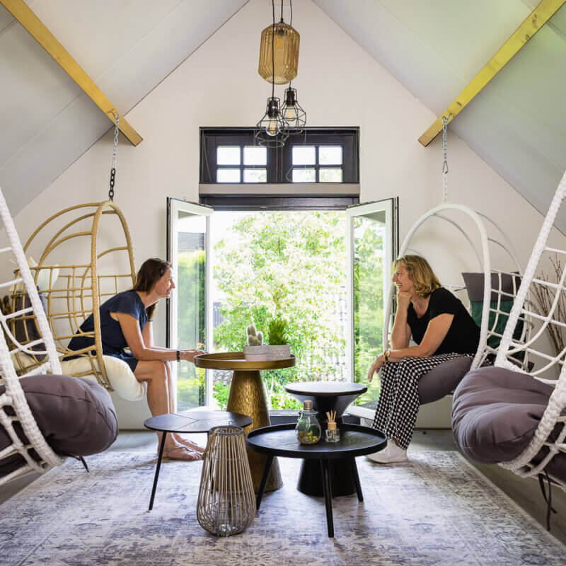 Gesprek in de bovenruimte van KIEM met hangstoelen en uitzicht op het groen